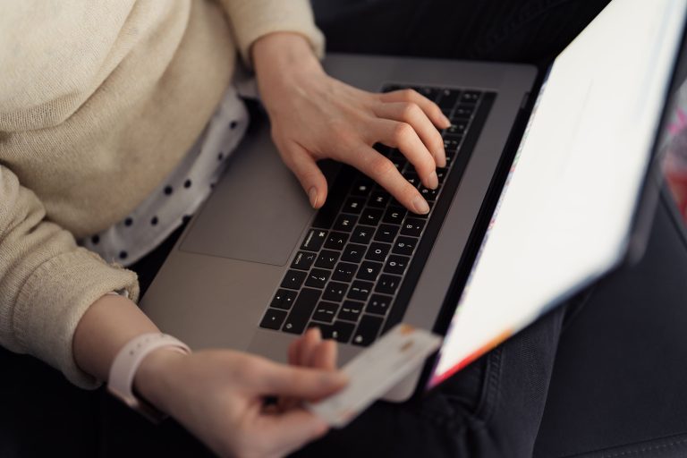 woman sitting on a laptop. Credit card in the right hand, doing online-shopping